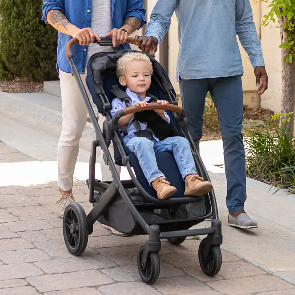 Parents stroll with child in Cruz V2 toddler seat