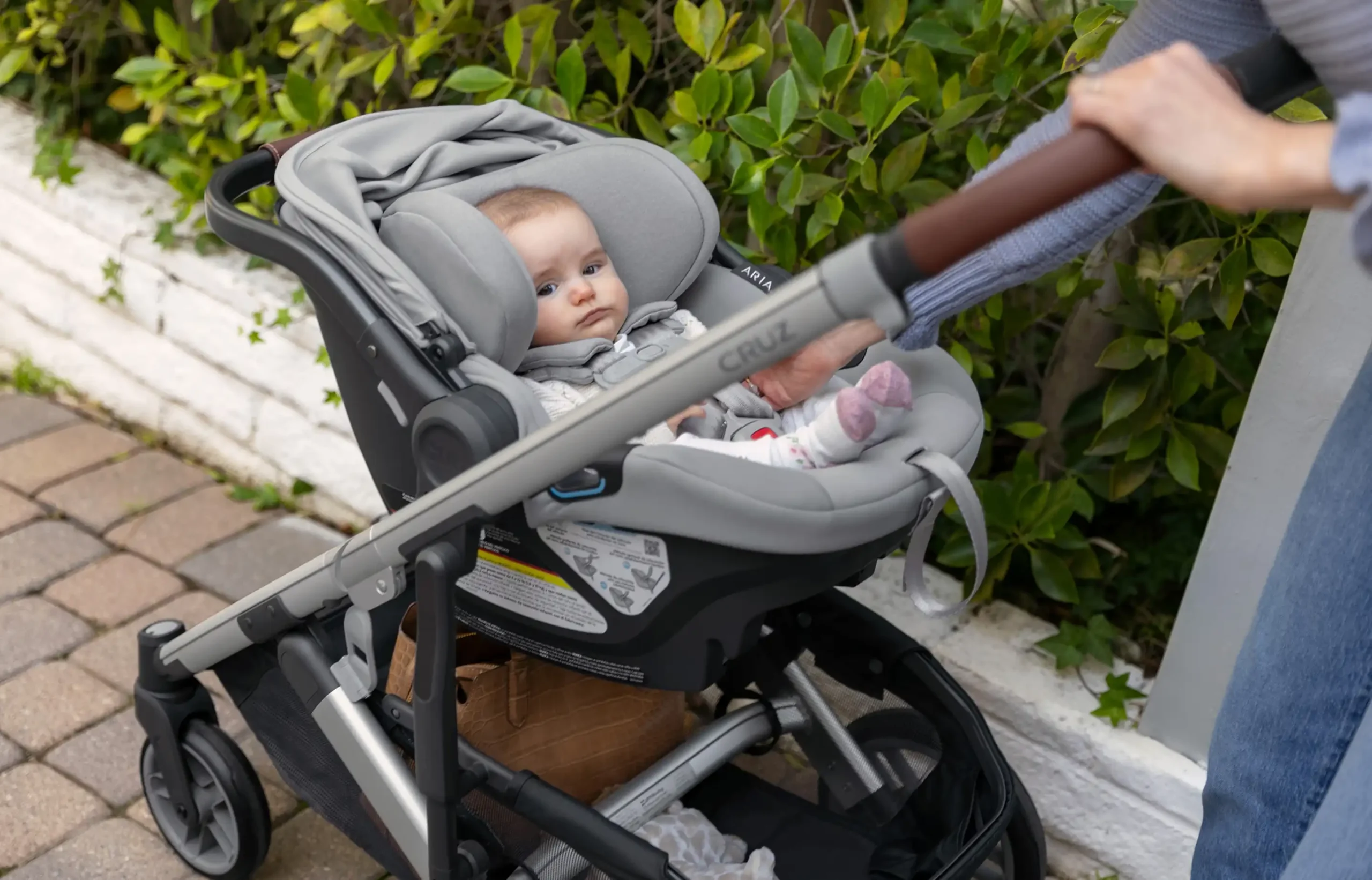 Parent strolling with infant in Cruz v2 Travel System with direct attachment of Aria infant car seat