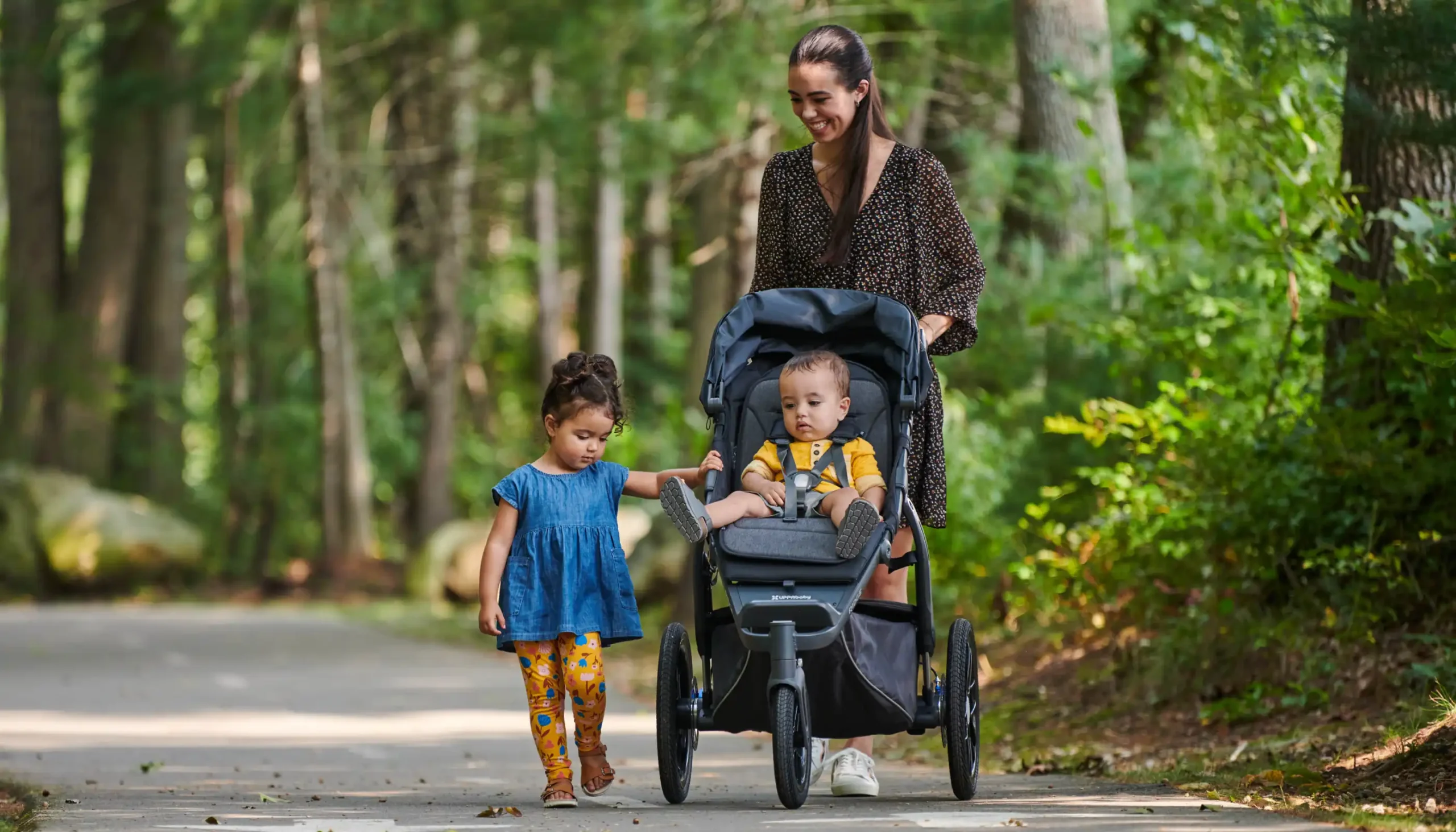 Child walking alongside parent pushing Ridge stroller with second child sitting in Toddler Seat with Reed Reversible Seat Liner