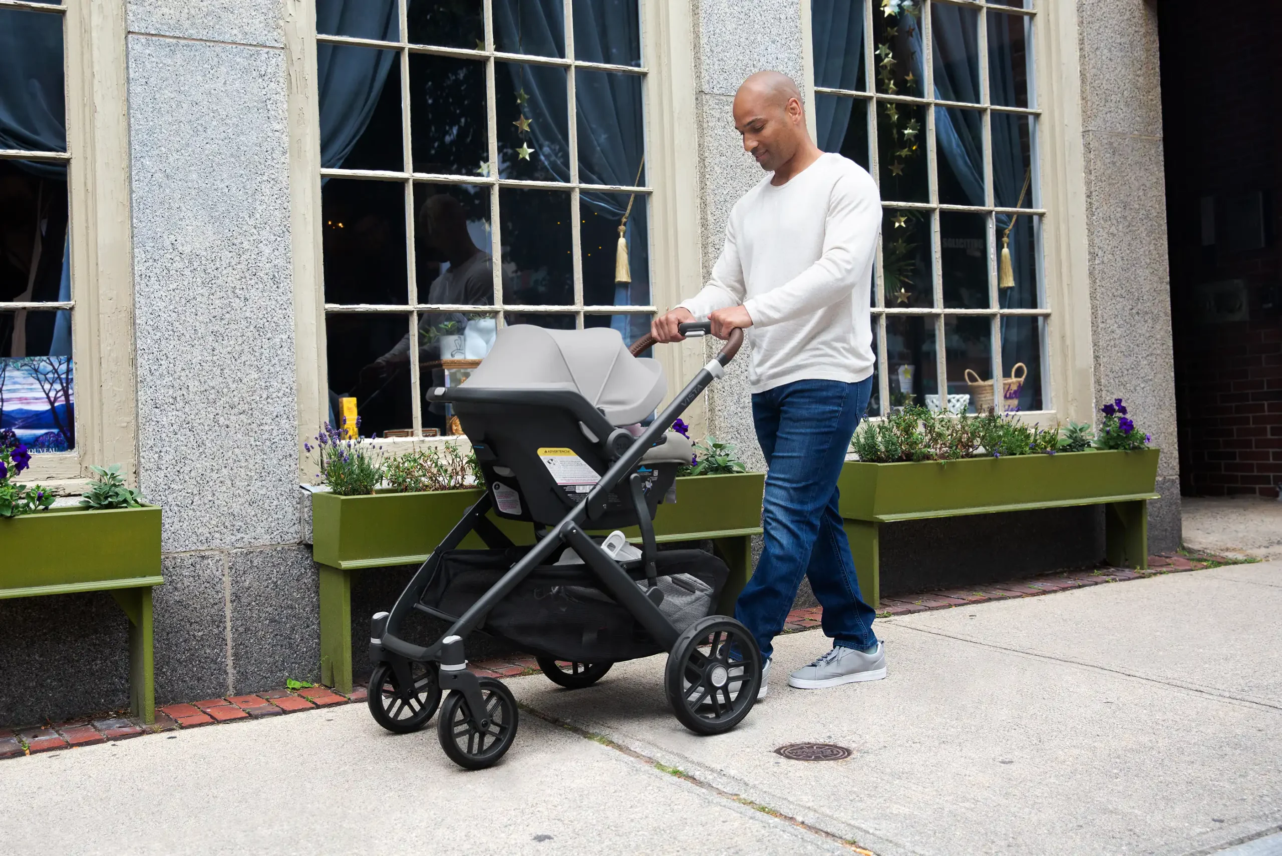 A man strolls with his child safely secured in a Mesa Max carrier attached directly to a Vista V2 travel system, easily allowing him to go from drive to stroll