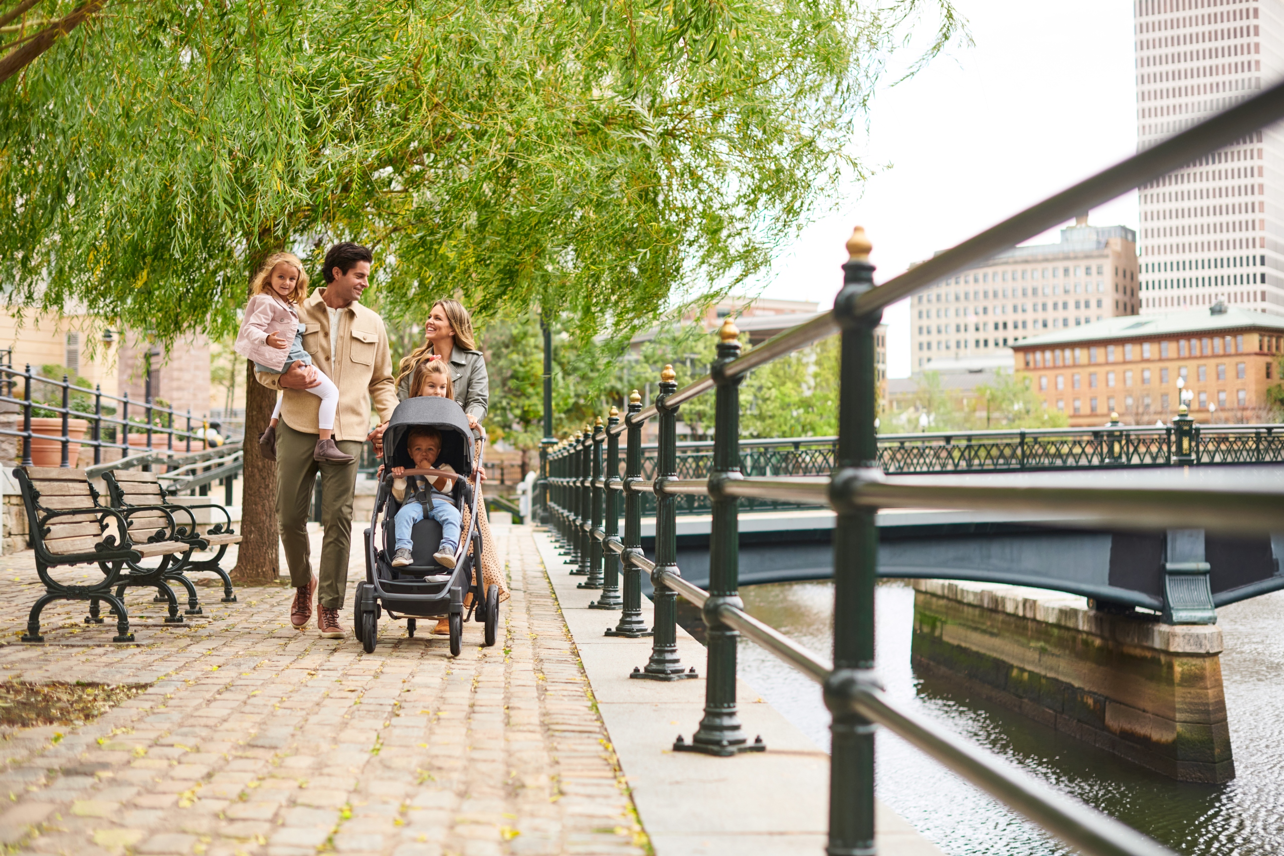 A family enjoying a walk by the river with their children in an UPPAbaby Vista V2 Stroller.