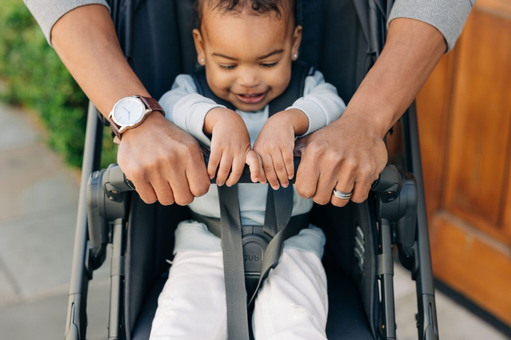 A child smiling while sitting safely in an UPPAbaby Vista V2 Stroller.