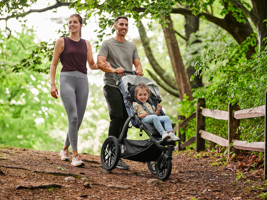 A mother and father adventuring with their little one in an UPPAbaby Ridge Stroller.