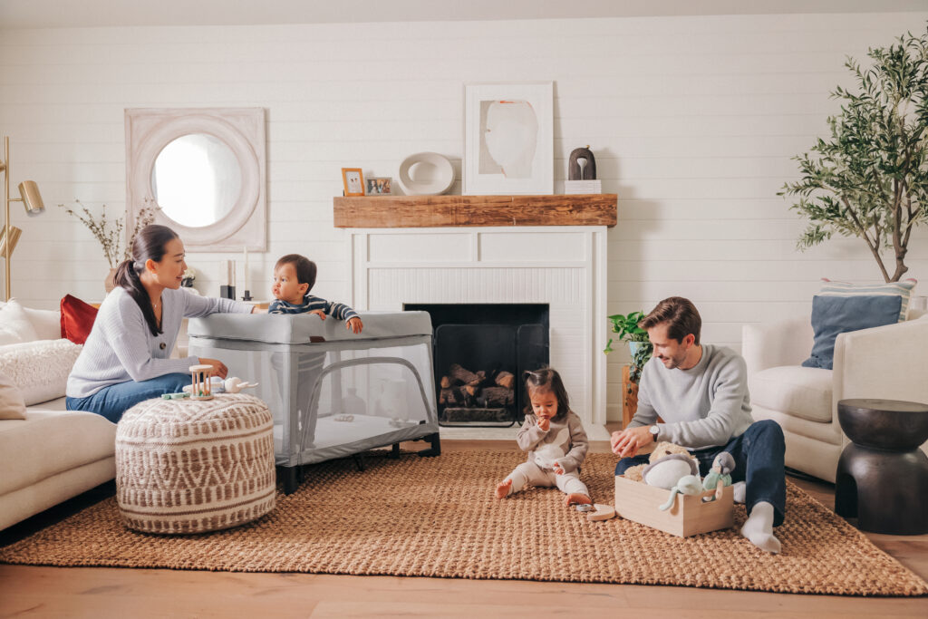 A family in their living room spending quality time together beside an UPPAbaby Remi Playard.