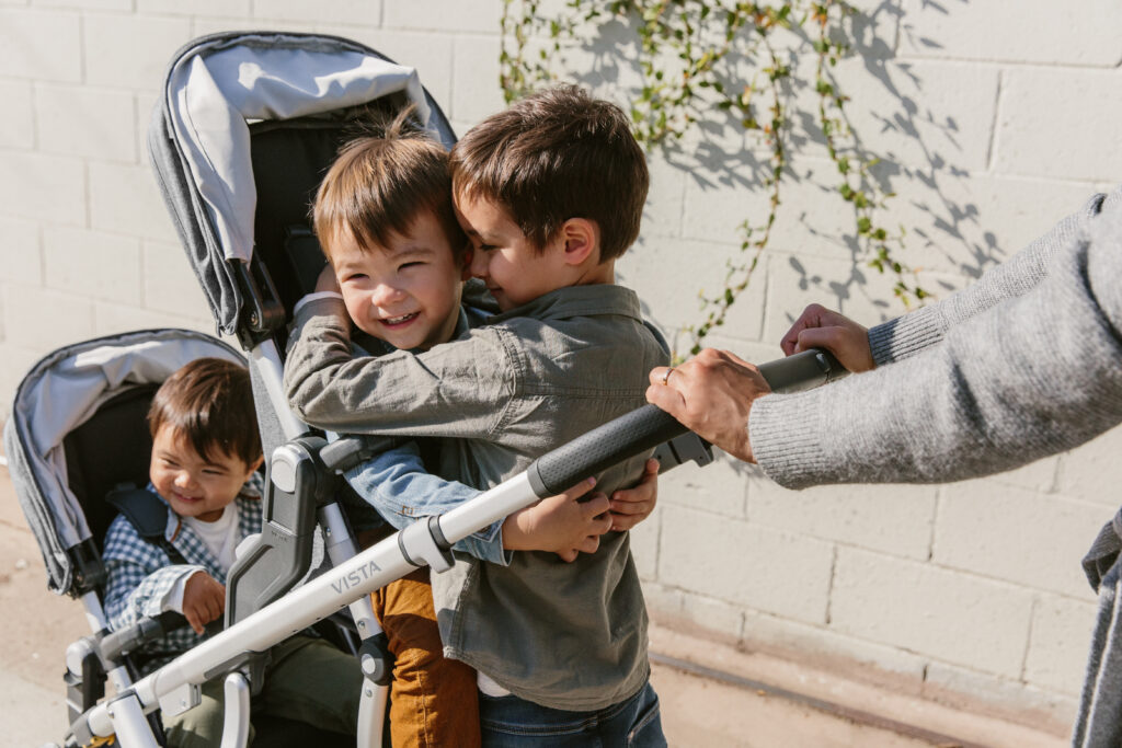 Three children laughing and smiling in their UPPAbaby Vista V2 Full Size Stroller