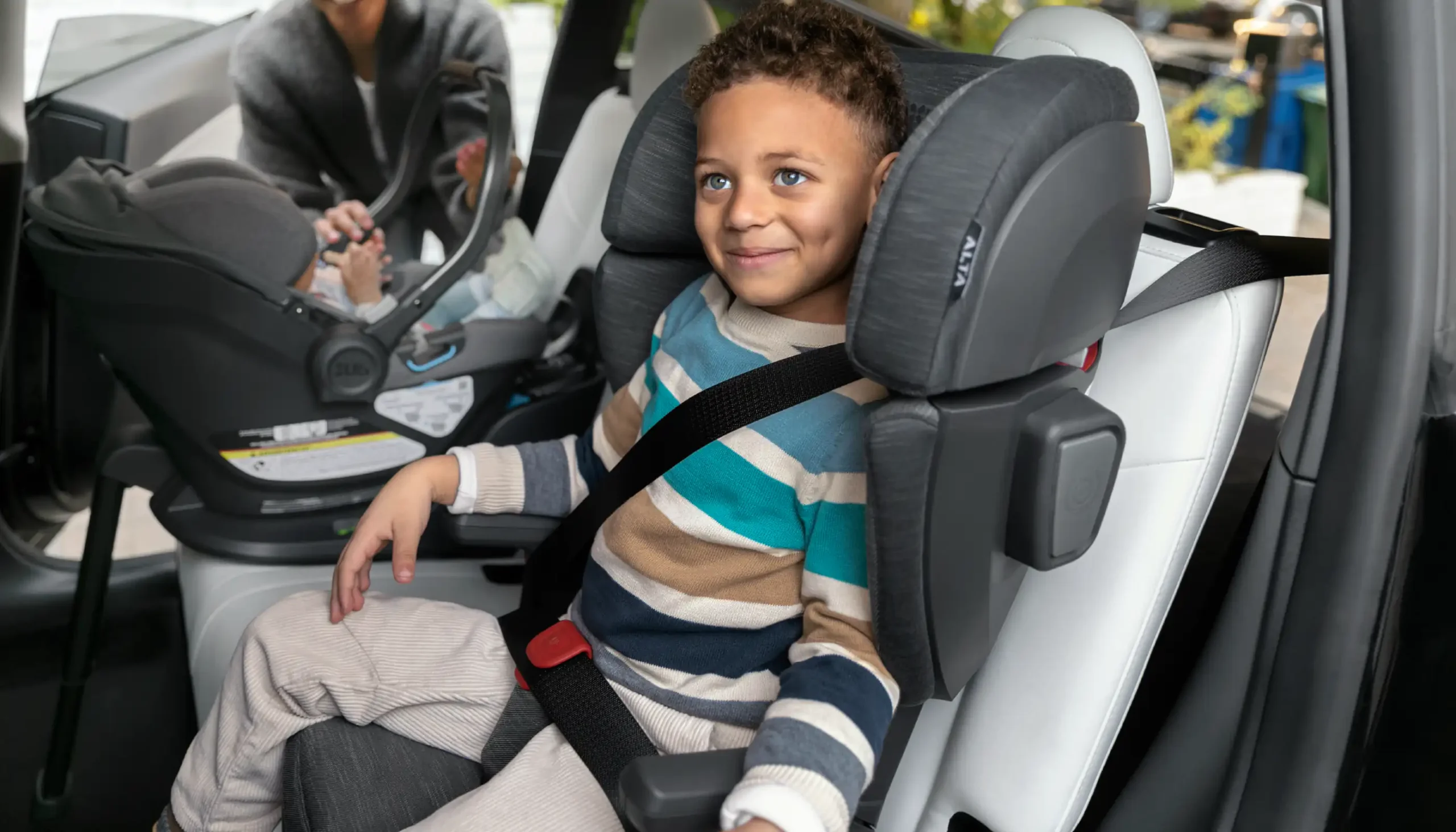 A happy child secured in the Knox Convertible Car Seat, supported by the elevated ergonomic dual armrests designed to enhance interaction and allow for the child to get in and out of their seat on their own