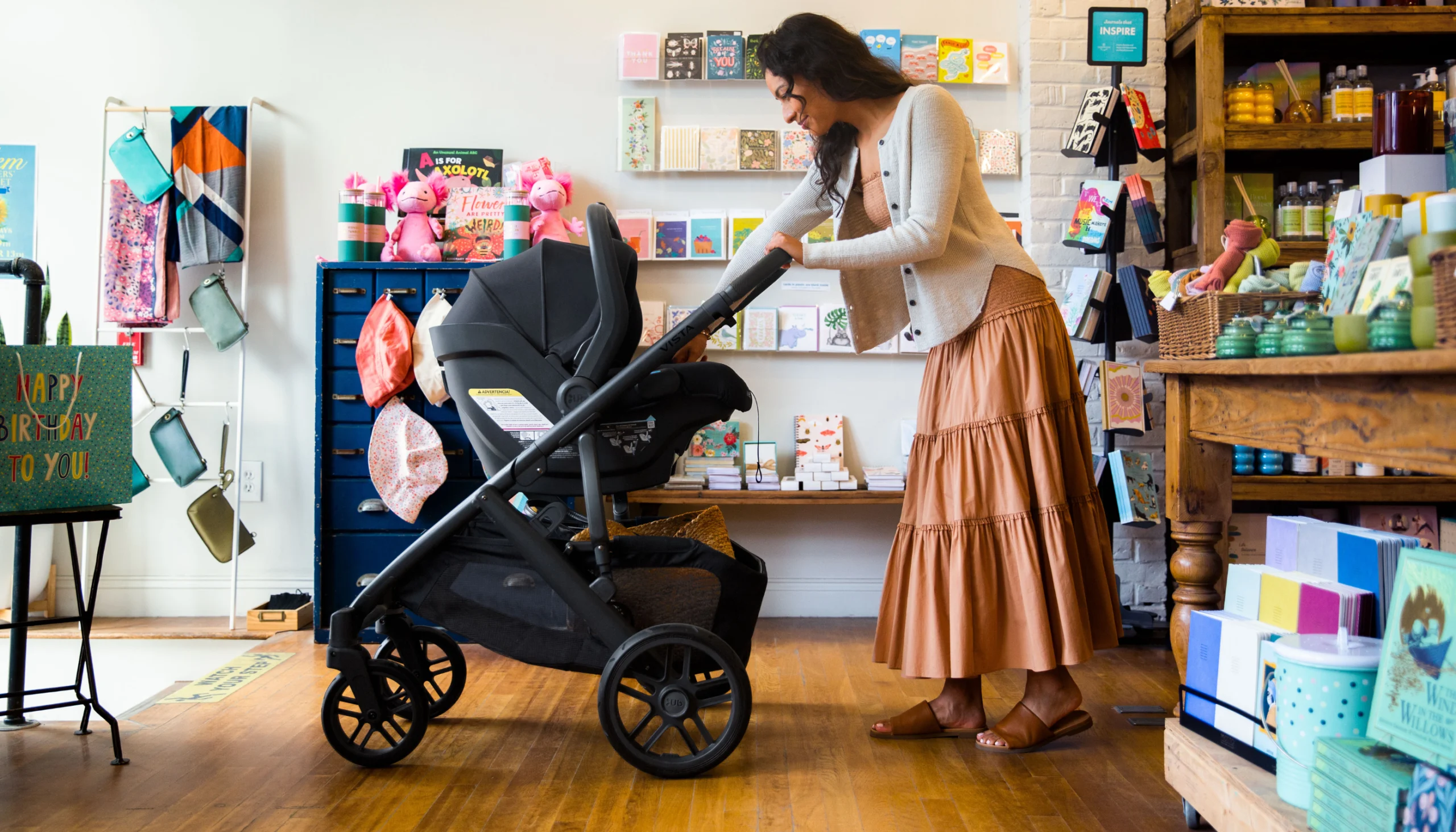 A mother smiles and engages with her infant in a Mesa car seat attached parent-facing in the upper position of a Vista stroller