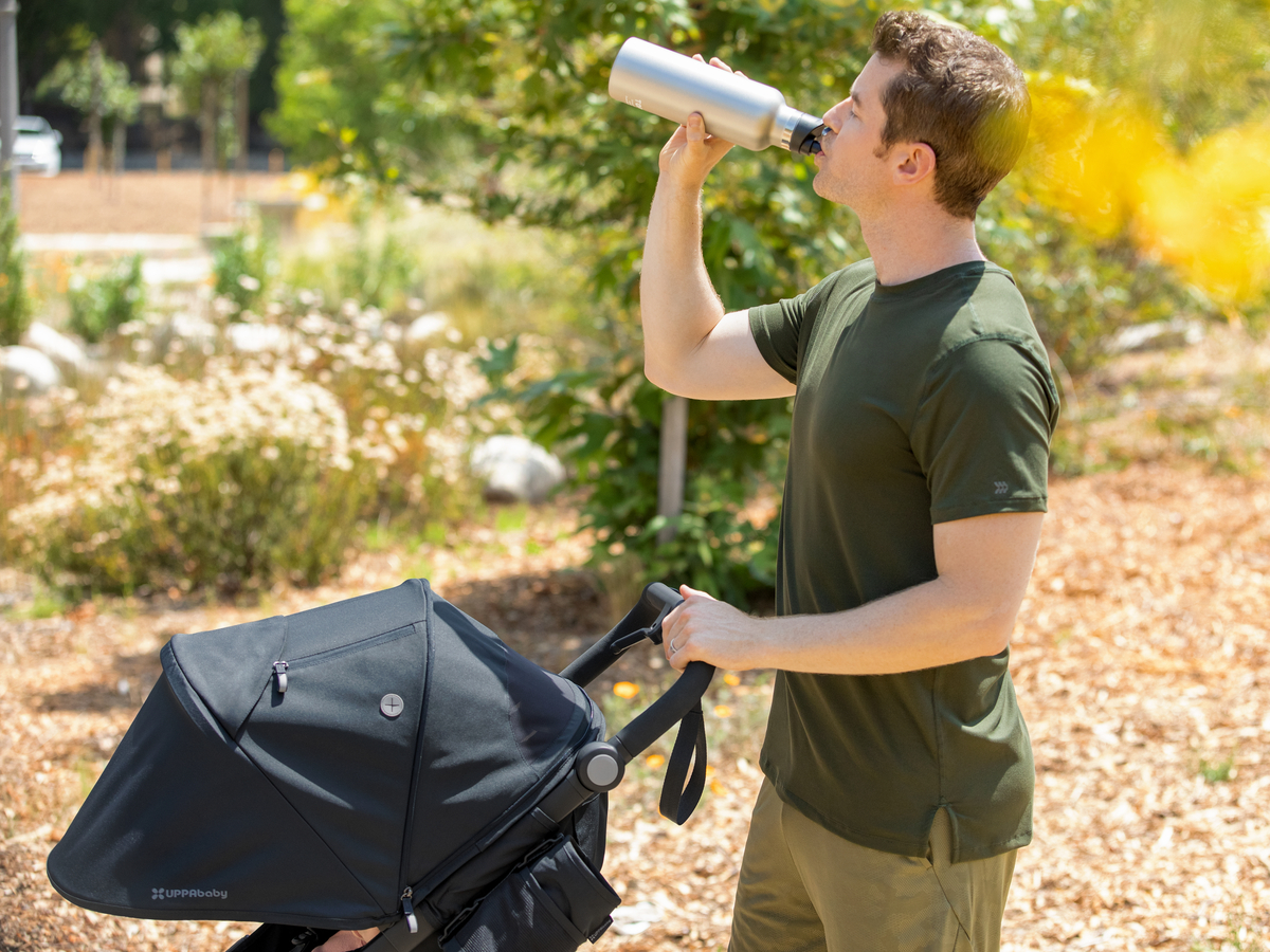 A man drinks water after running with the Ridge jogging stroller.